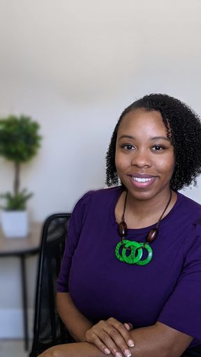 SEO Geneva Bell wearing a purple shirt and green necklace.
