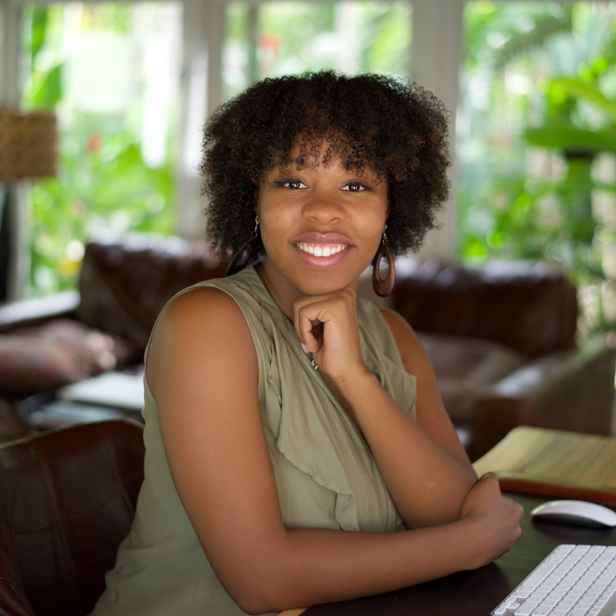 SEO Geneva Bell wearing a purple shirt and green necklace.